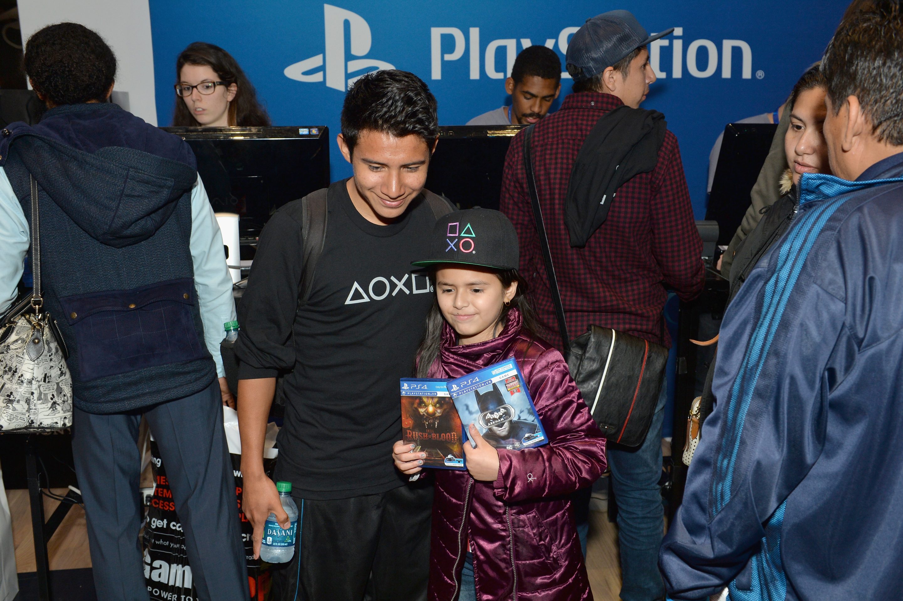 A child holds two PlayStation game cases next to an adult wearing a PlayStation shirt, from Sony's own promotional imagery for physical game ownership.