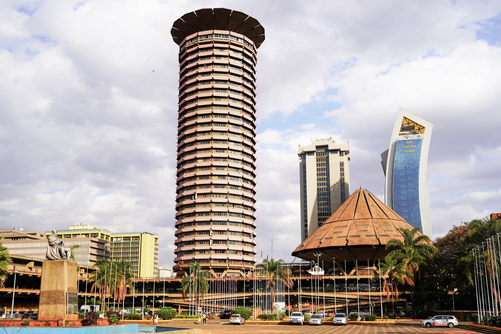 The Kenyatta International Convention Centre in Nairobi — a cylindrical tower flared into a saucer-shaped crown, beside a cone-roofed amphitheater, both read as African-inspired forms
