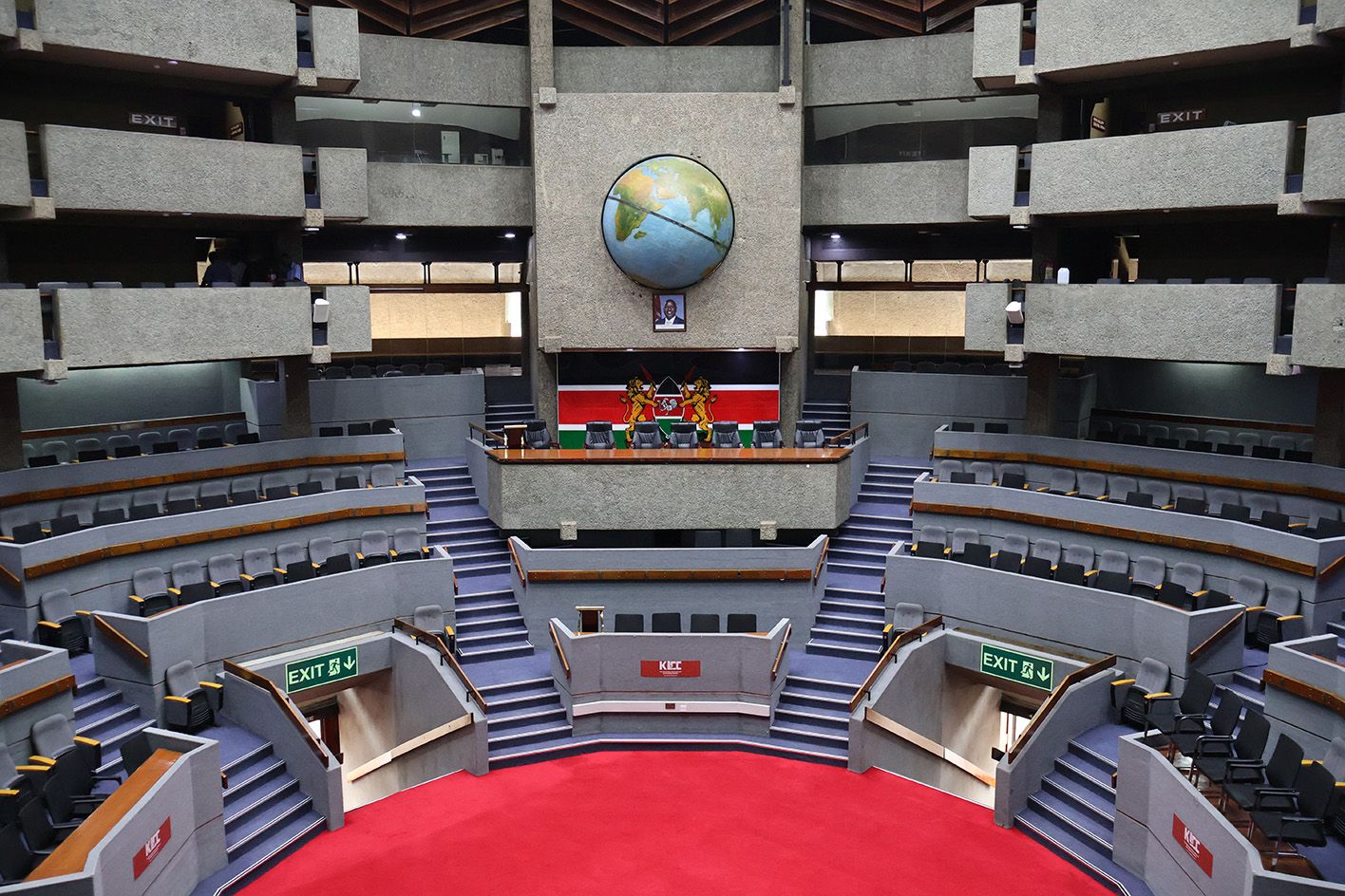 The KICC's circular plenary hall, red-carpeted, with Kenya's coat of arms and a large globe mounted above the podium