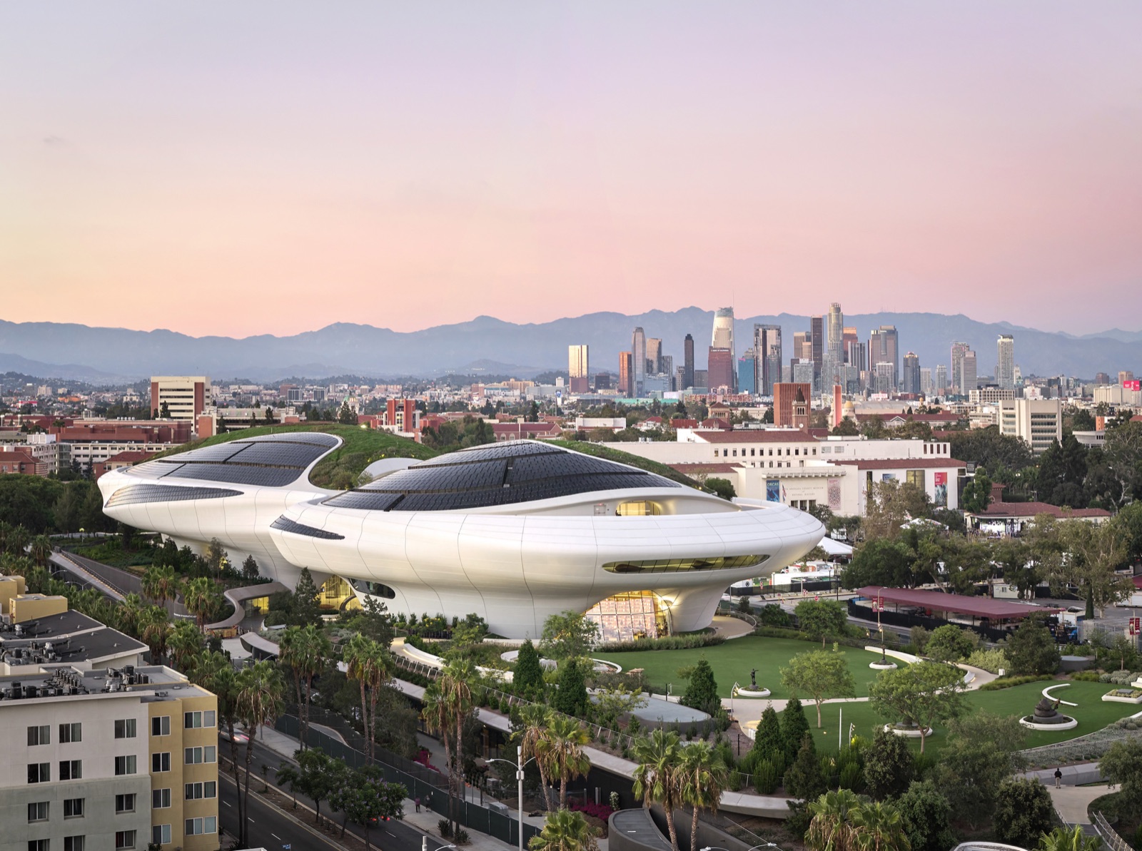The Lucas Museum of Narrative Art at dusk, its cloud-like white form overlooking the Los Angeles skyline