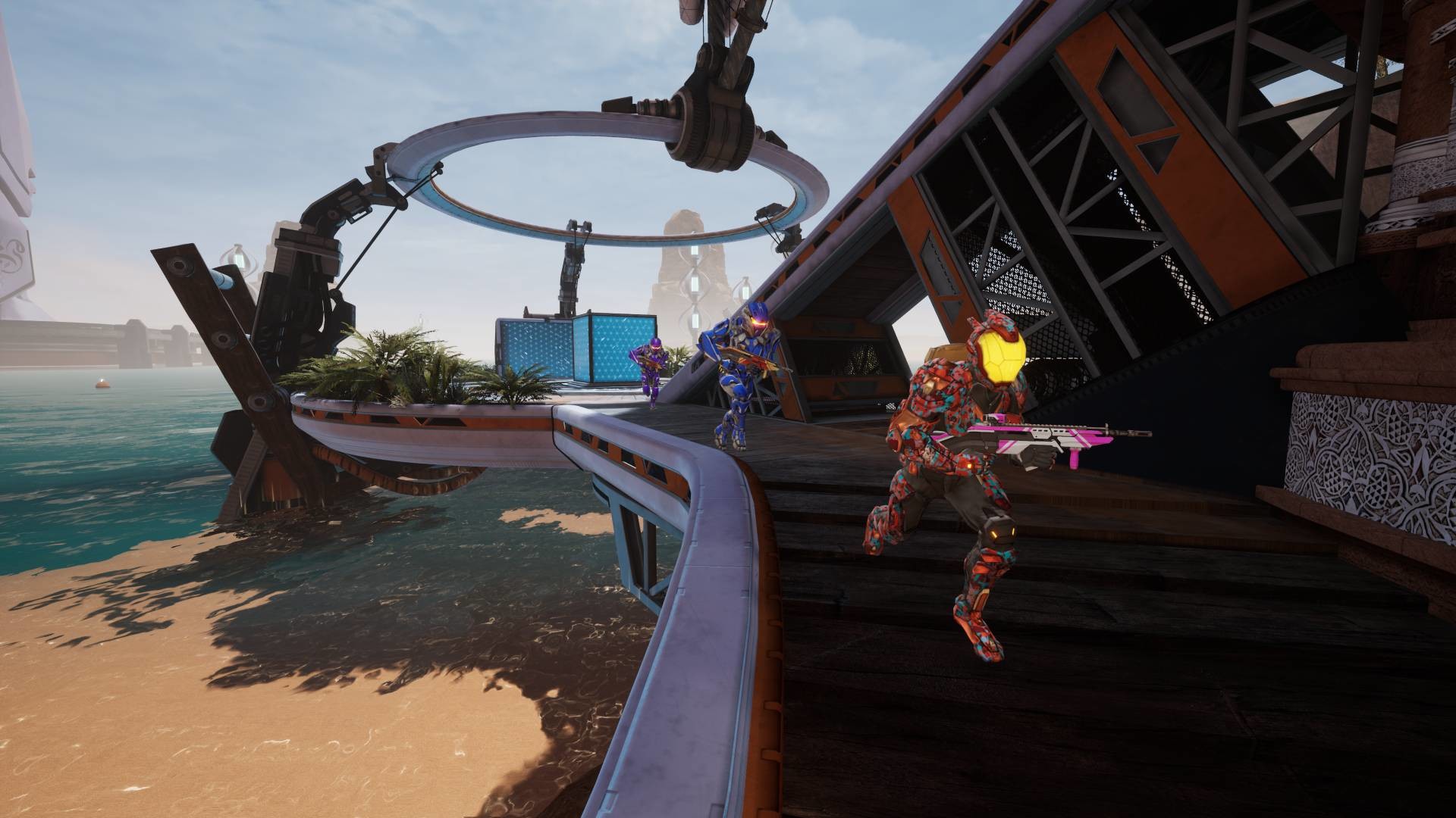 Splitgate gameplay screenshot showing three armored players with weapons drawn on a coastal platform, a large ring-shaped structure visible in the background